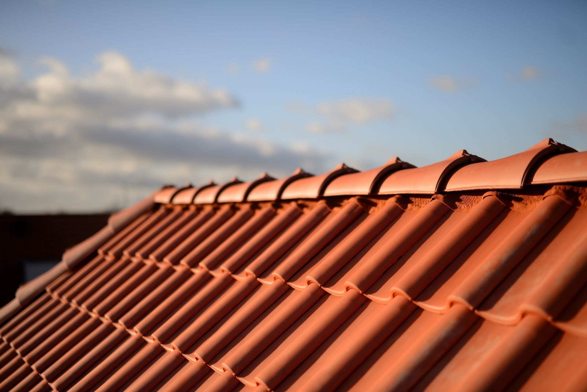 Vue sur un toit de tuiles en terre cuite sous un ciel bleu nuageux