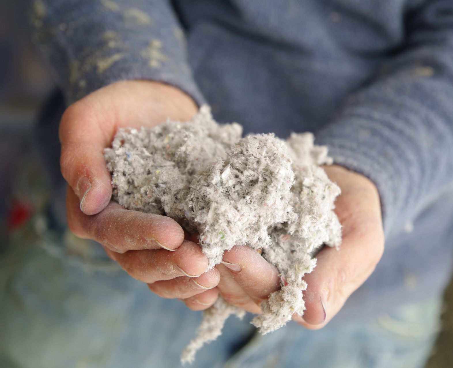 Isolant soufflé dans le creux des mains d'un artisan
