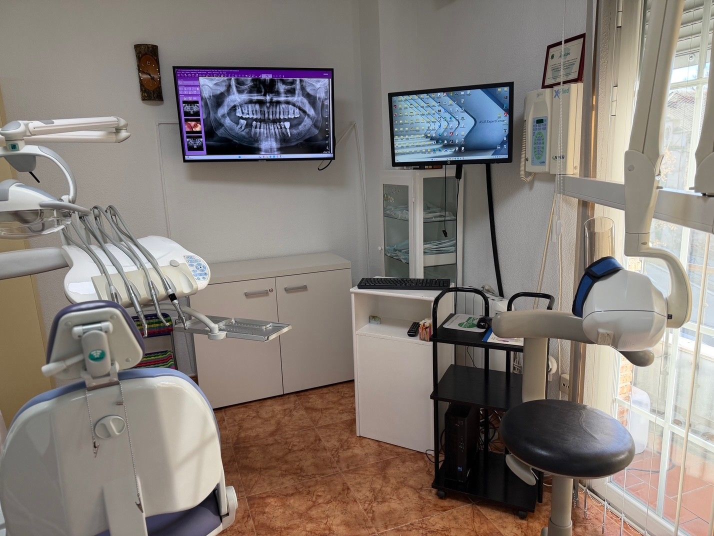 Dentista examinando una radiografía dental, sosteniendo la radiografía frente a una fuente de luz para examinarla de cerca.