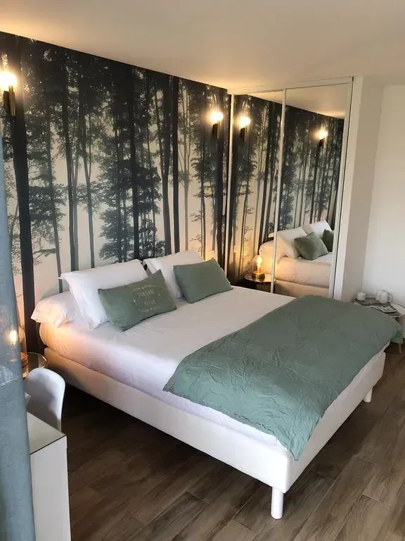 Chambre avec lit blanc, papier peint à motif de forêt et miroirs reflétant la pièce.