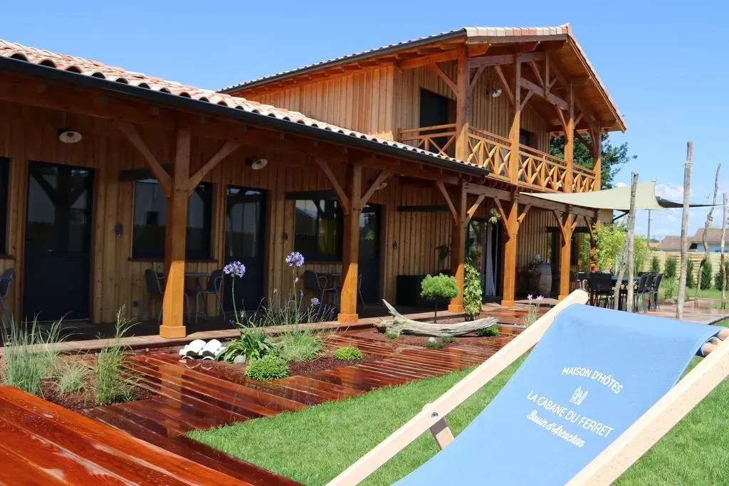 Bâtiment en bois de style chalet avec une véranda, chaise de jardin au premier plan.
