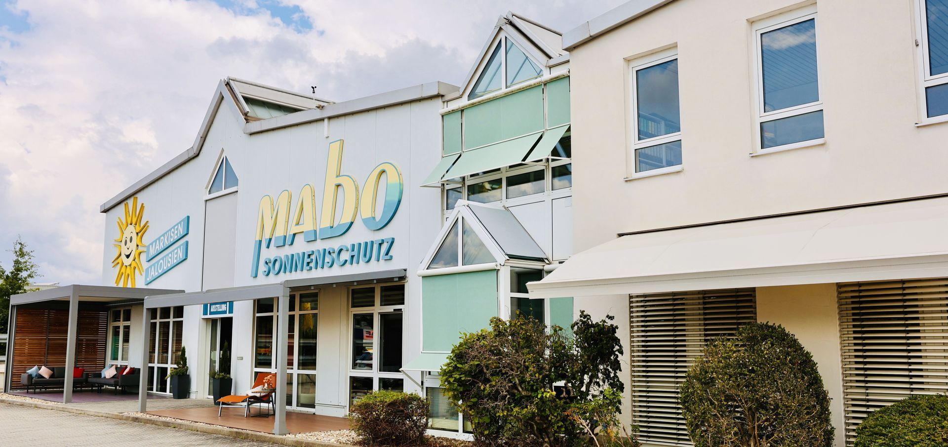 Außenansicht eines Gebäudes mit einem großen Schild mit der Aufschrift „Mambo“. Der Himmel ist bewölkt.