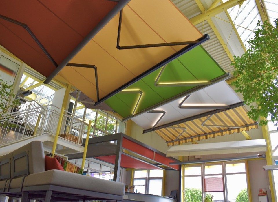 Bunte, einziehbare Markisen im Inneren eines hell erleuchteten Gebäudes.