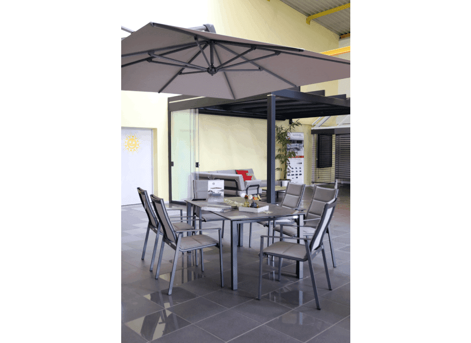 Terrassenmöbel-Set mit Sonnenschirm, Tisch und Stühlen unter einer großen, grauen Überdachung.