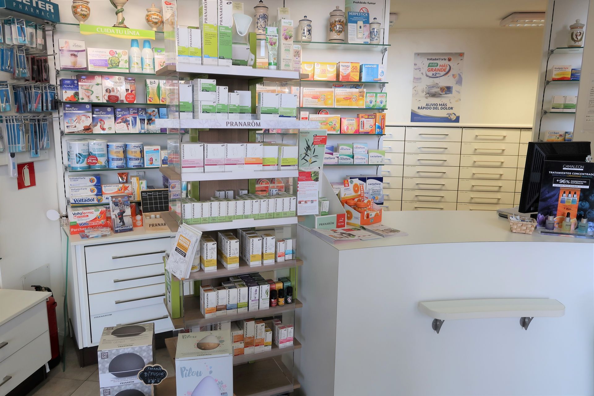 Una farmacia con muchos estantes y un mostrador.