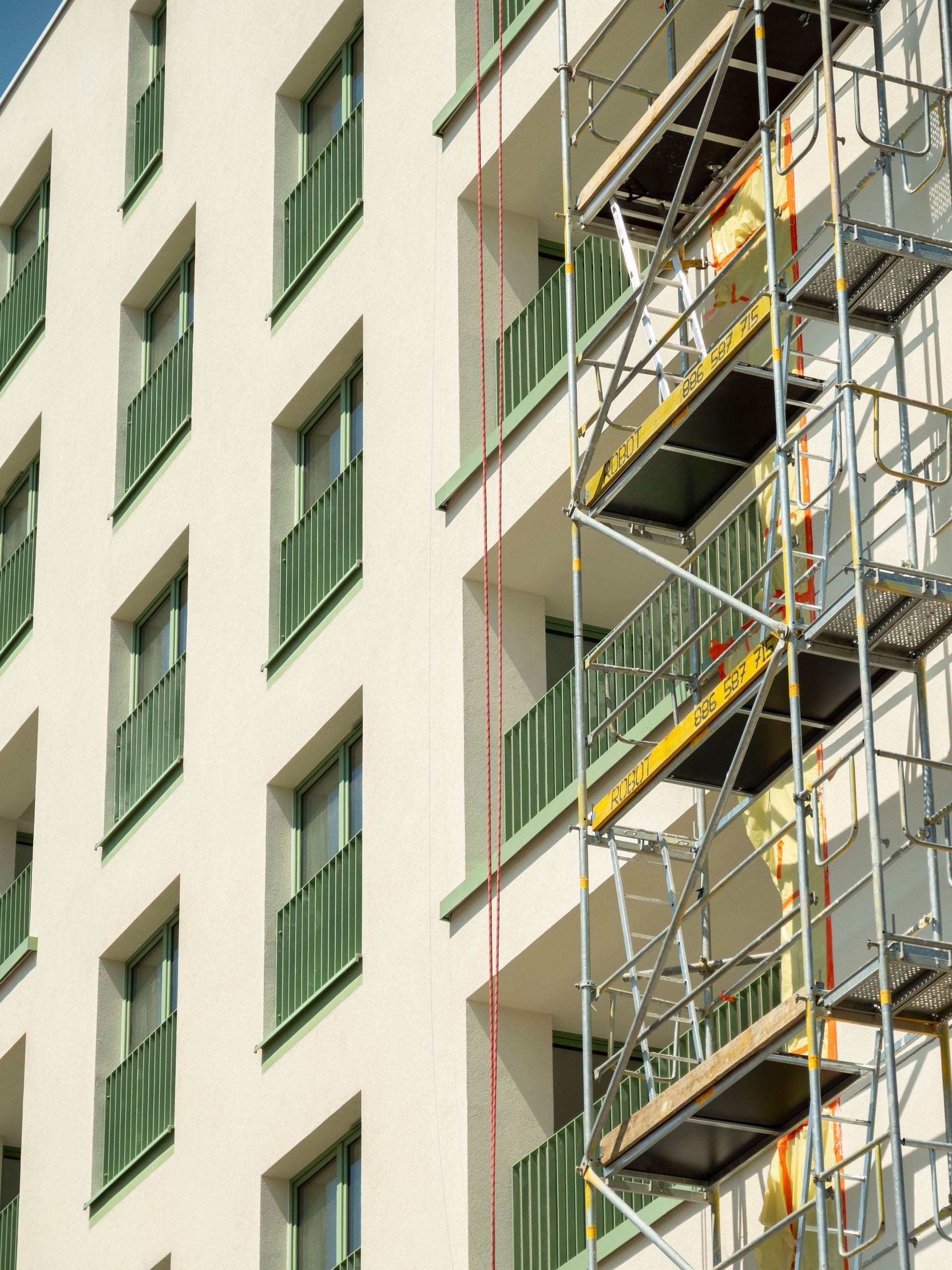 Die Hausfassade befindet sich im Bau und ist mit Gerüsten und freiliegenden Ziegelwänden versehen.