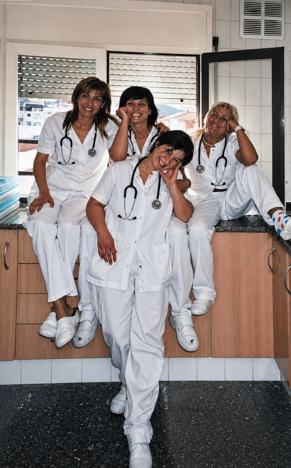 Cuatro miembros del personal médico con uniformes blancos posando juntos en la sala de descanso del hospital.