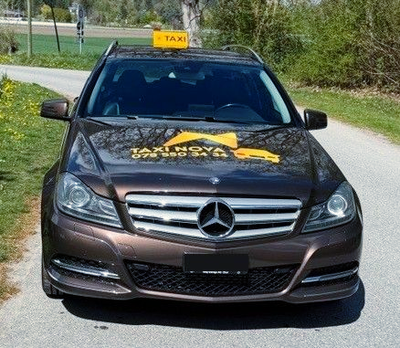 Ein braunes Mercedes-Taxi parkte auf einer Asphaltstrasse. Auf der Motorhaube prangte ein Schild mit der Aufschrift „Taxi Nova“ und eine Telefonnummer.