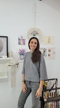 Dona dreta en un estudi d'art lluminós al costat d'un cavallet decorat i obres d'art emmarcades