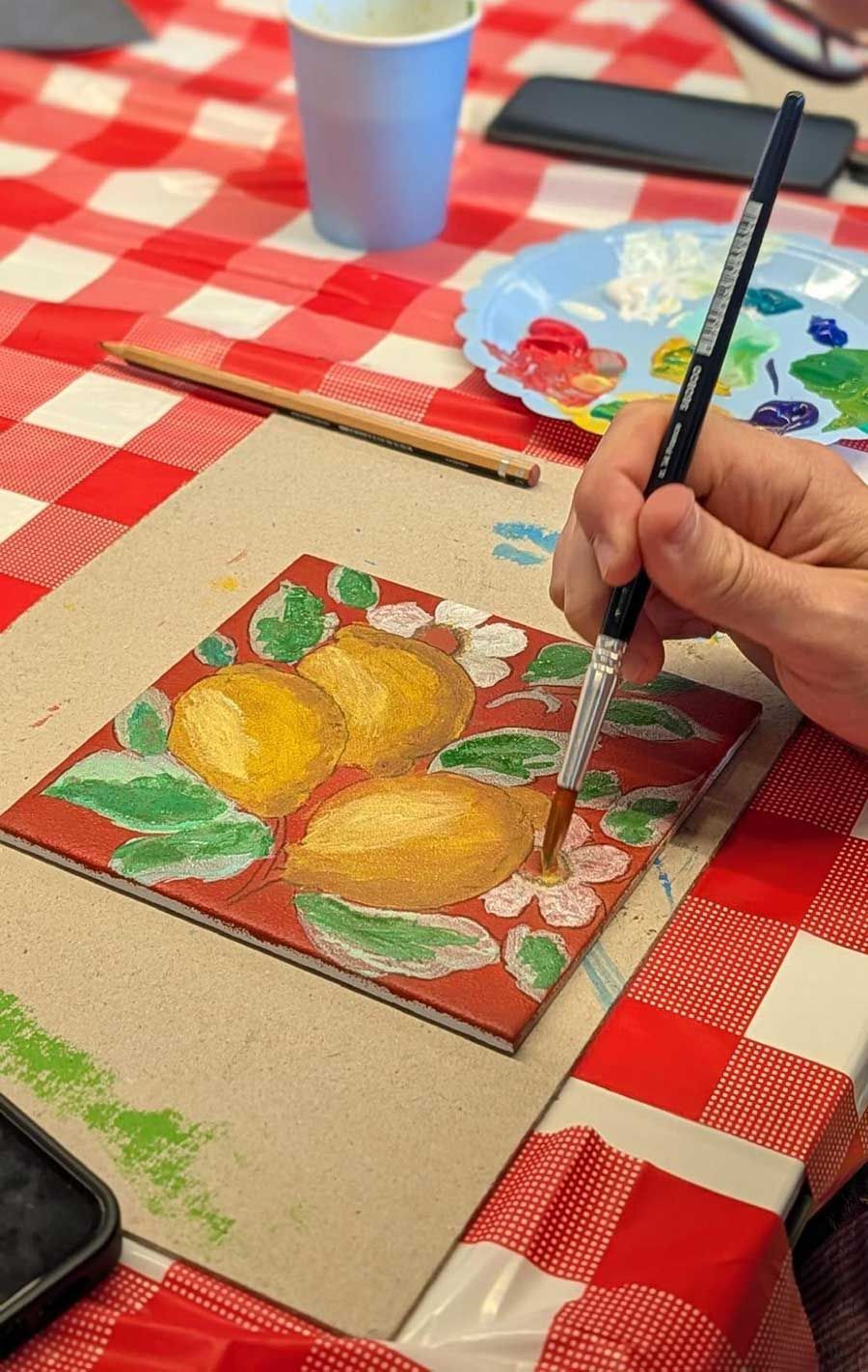 Pintant a mà una natura morta de peres sobre un petit llenç en una taula de quadres vermells