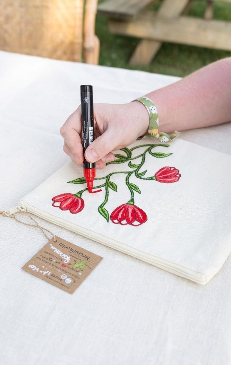 Pintant a mà flors de tulipes vermelles i tiges verdes sobre tela blanca amb un retolador negre