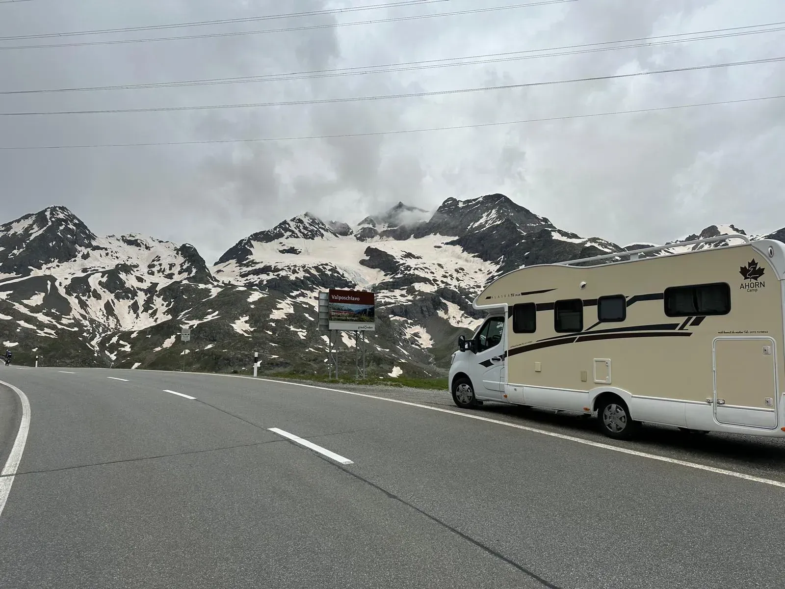 Ein Wohnmobil steht am Straßenrand, im Hintergrund sind Berge zu sehen.
