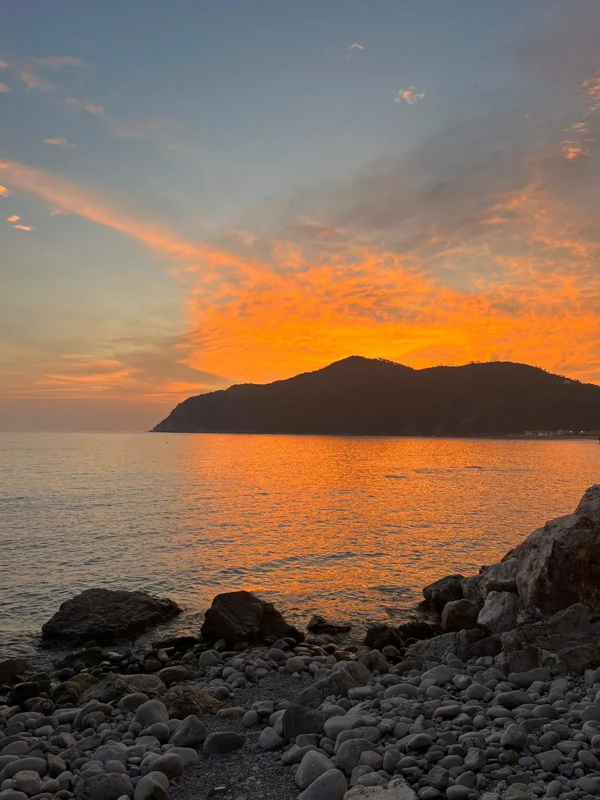 Ein Sonnenuntergang über dem Meer mit einem Berg in der Ferne.