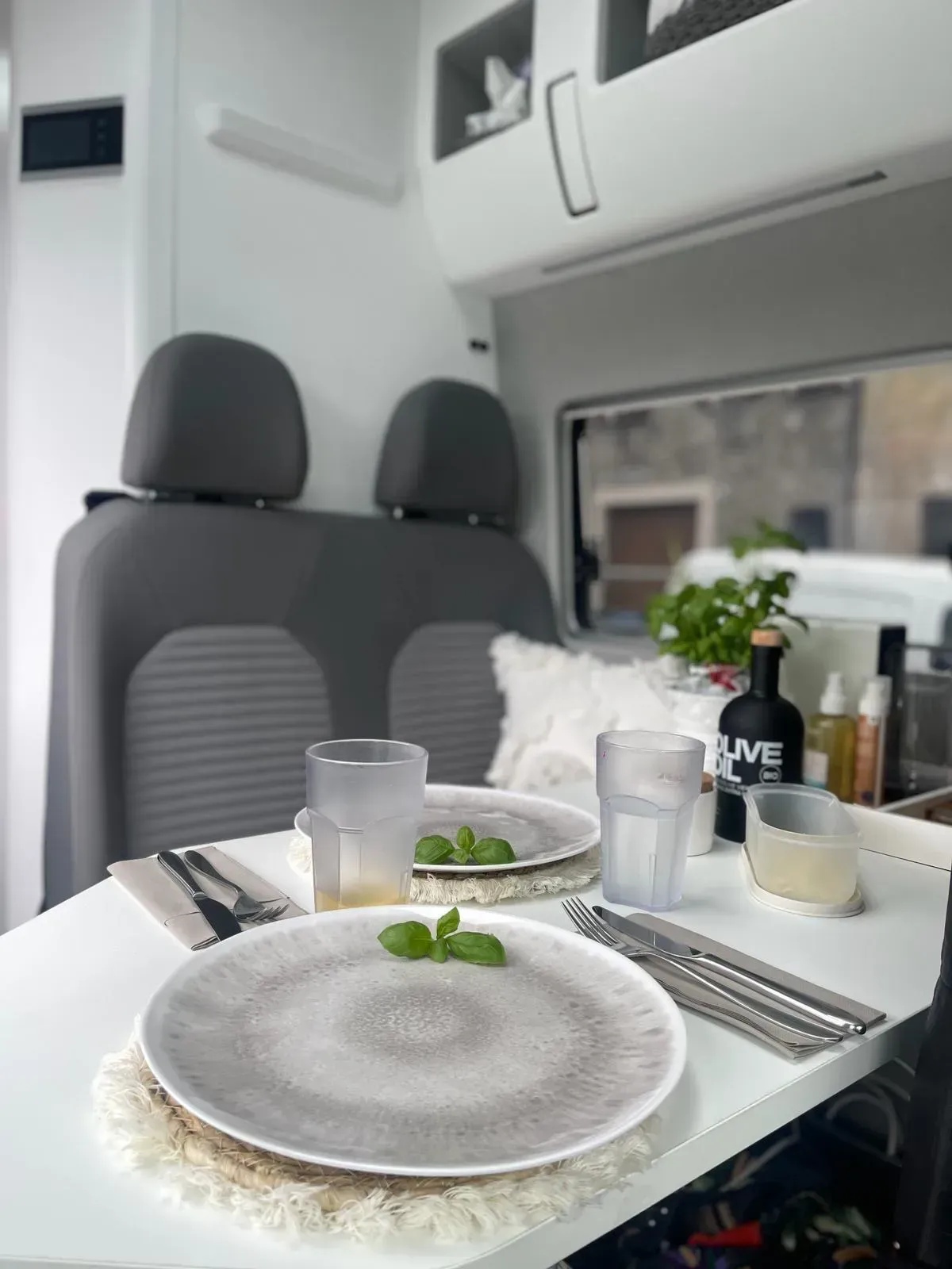 Ein Tisch mit Tellern, Gläsern und Besteck in einem Lieferwagen.