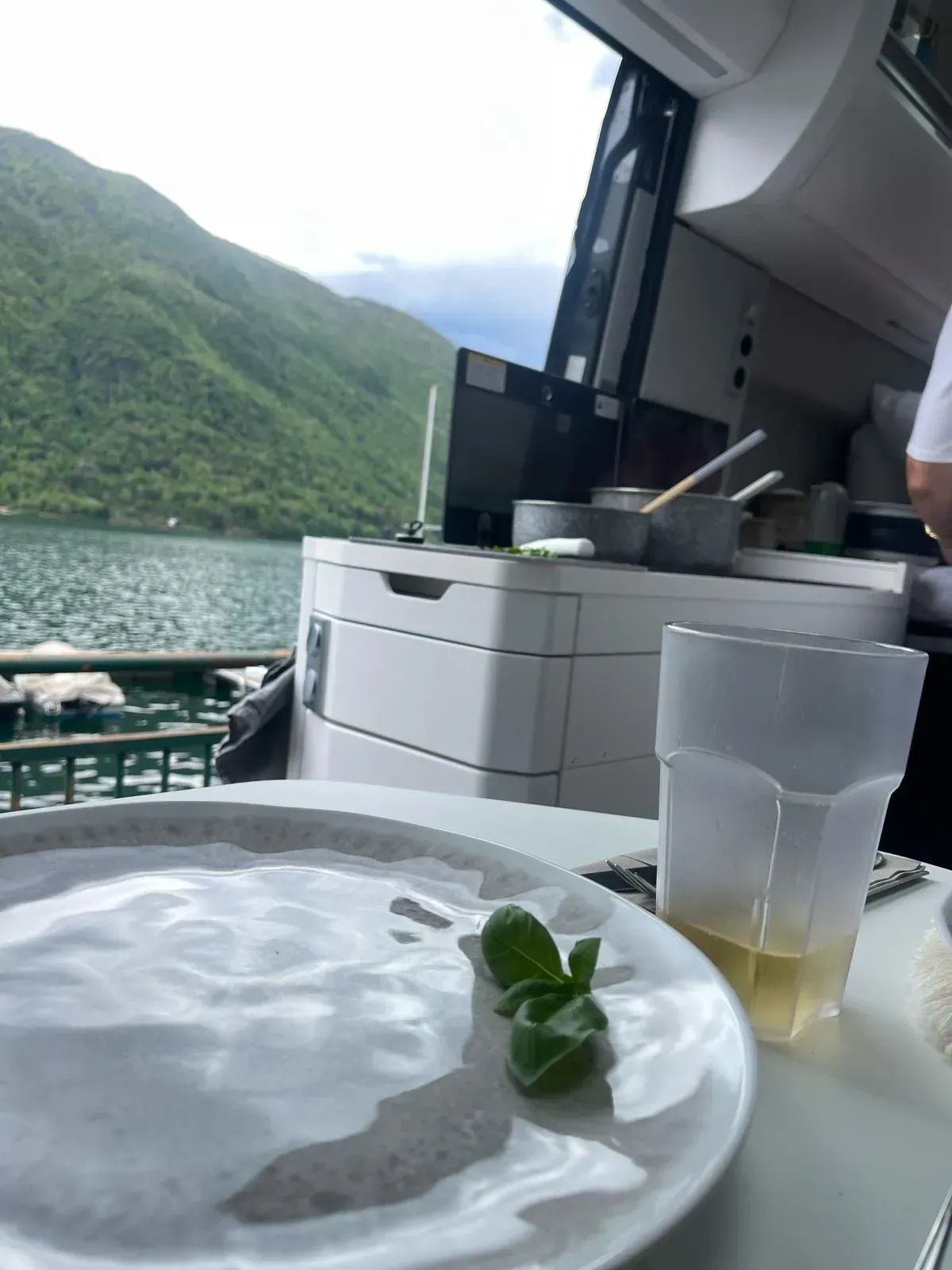 Ein weißer Teller mit einem grünen Blatt darauf steht auf einem Tisch