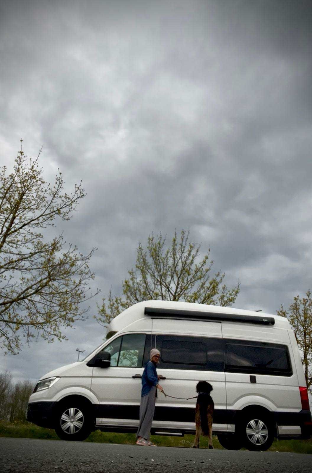 Ein Mann und ein Hund stehen neben einem weißen Lieferwagen.