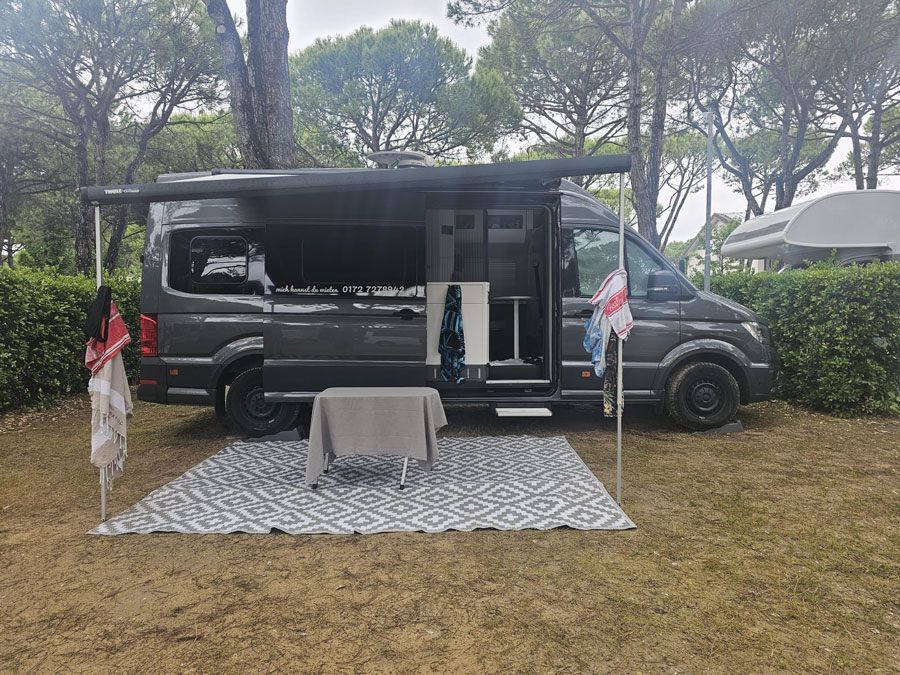 Ein Wohnmobil ist mit einem Tisch und Stühlen auf einer Rasenfläche geparkt.