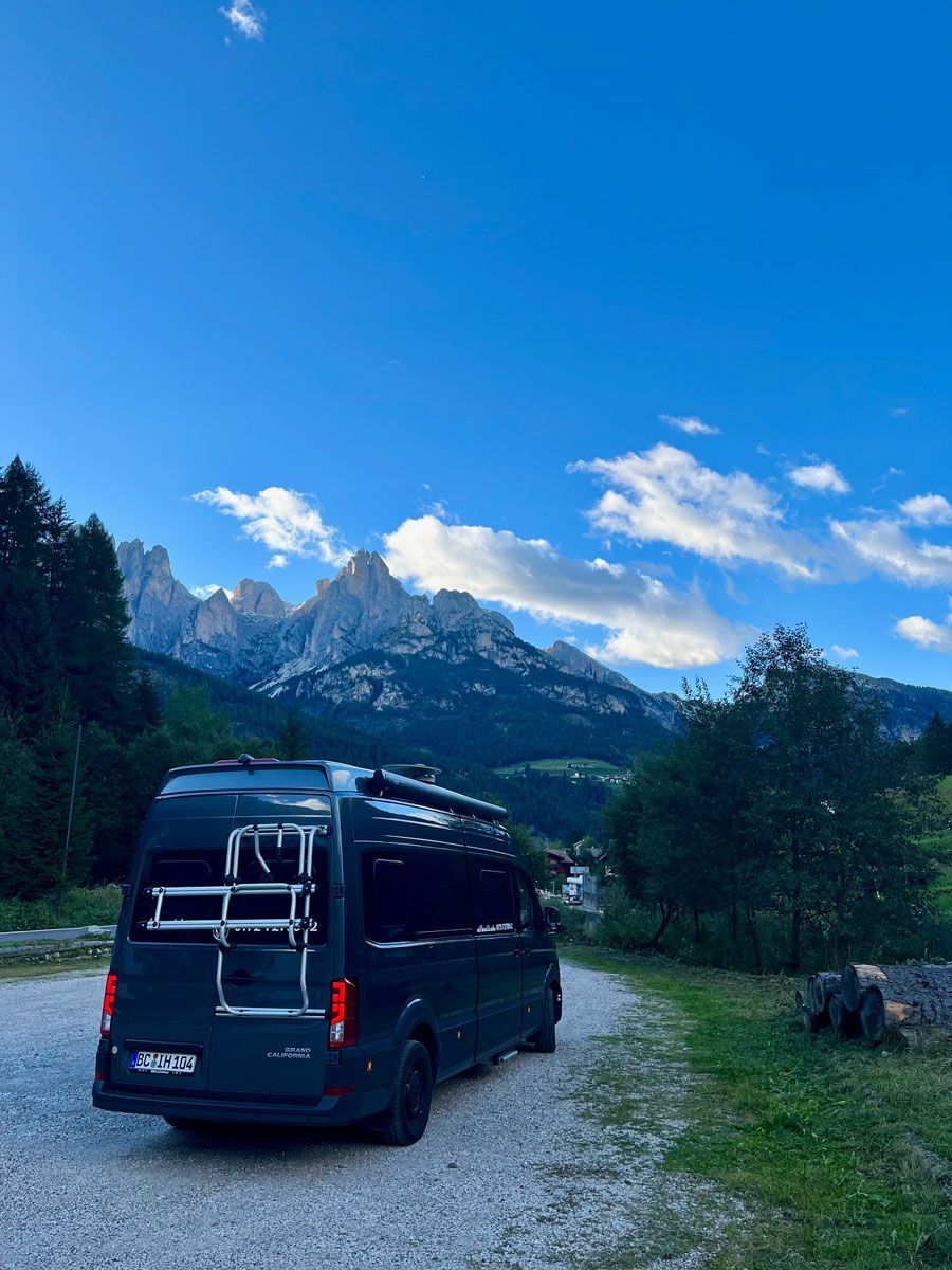 Ein schwarzer Lieferwagen mit einem Fahrradträger auf der Rückseite ist vor einem Berg geparkt.