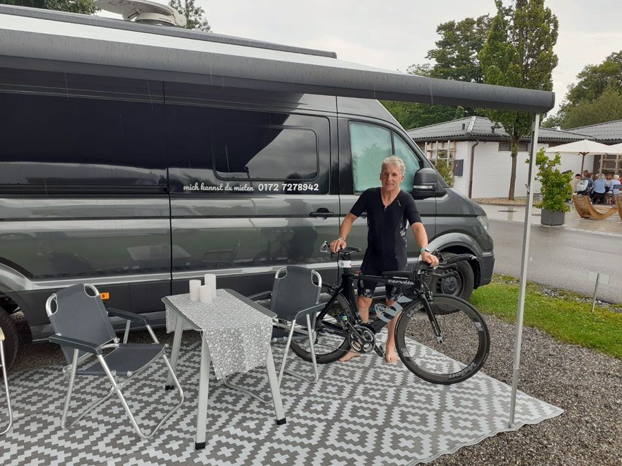 Ein Mann steht neben einem Fahrrad vor einem Lieferwagen.