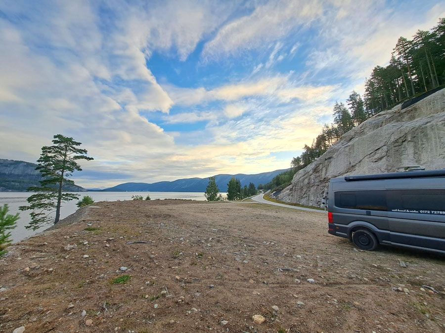 Ein Lieferwagen ist auf einer unbefestigten Straße neben einem See geparkt.