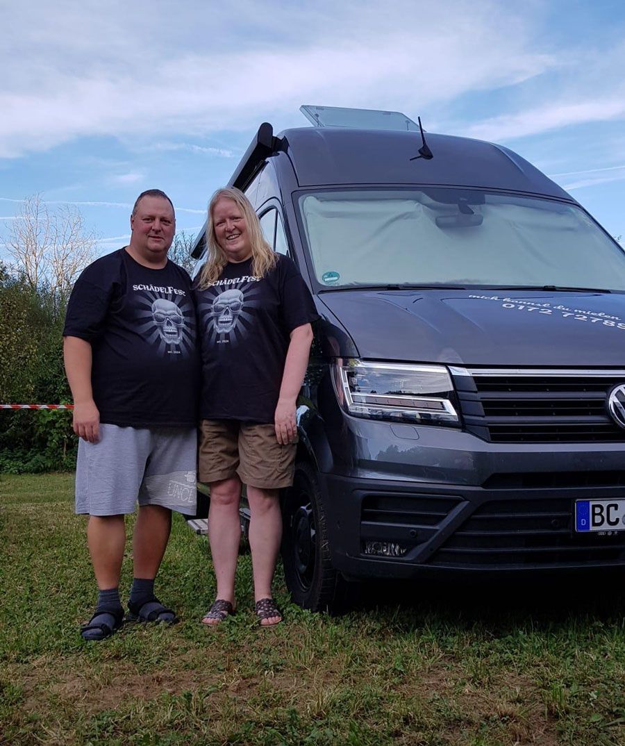 Ein Mann und eine Frau stehen vor einem Lieferwagen.