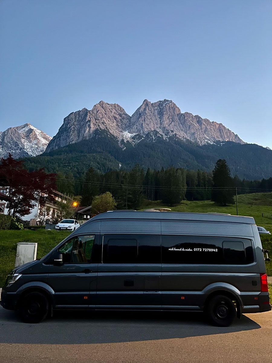 Ein schwarzer Lieferwagen parkt vor einem Berg.