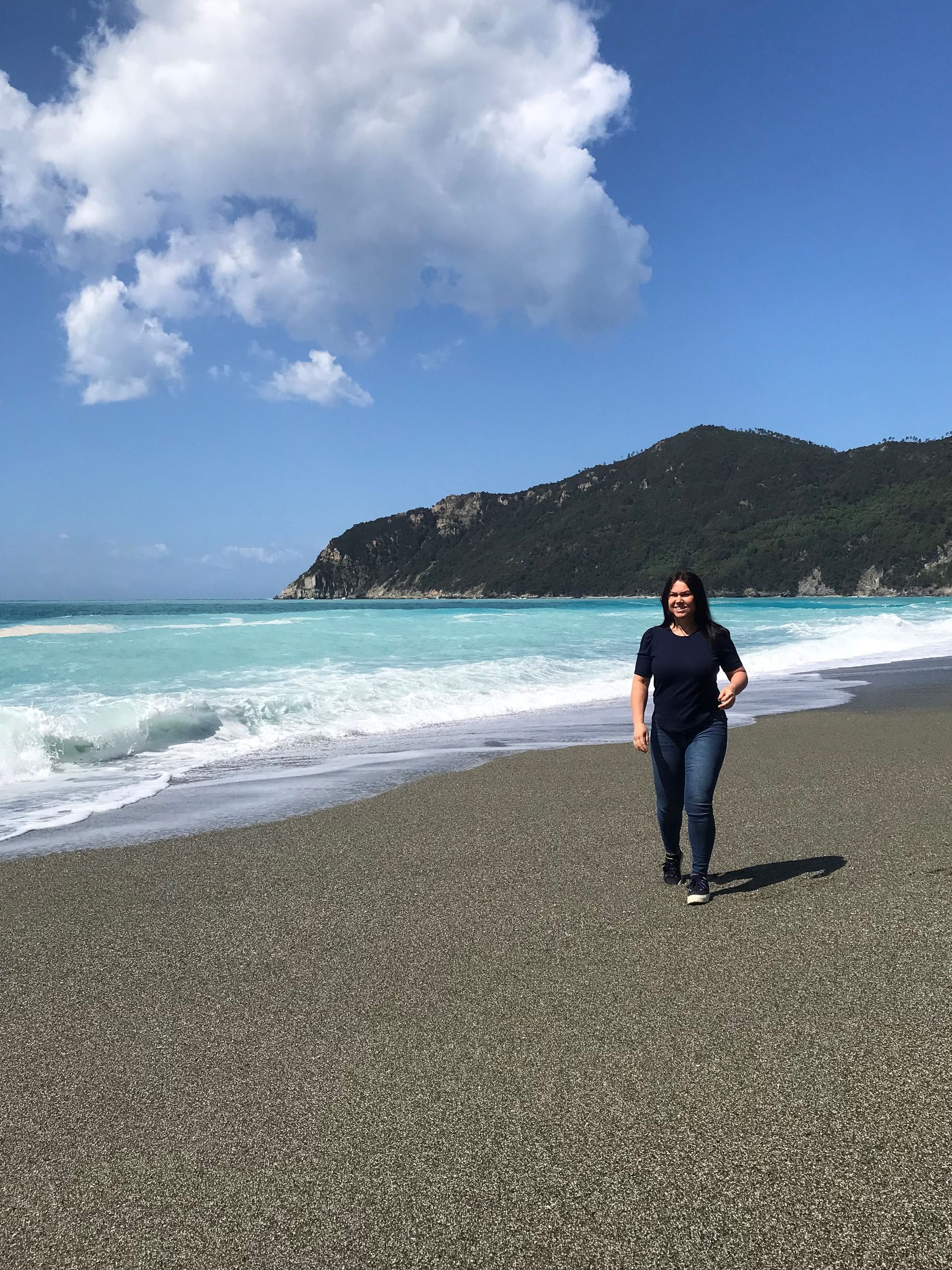 Eine Frau geht an einem Strand in der Nähe des Meeres spazieren.