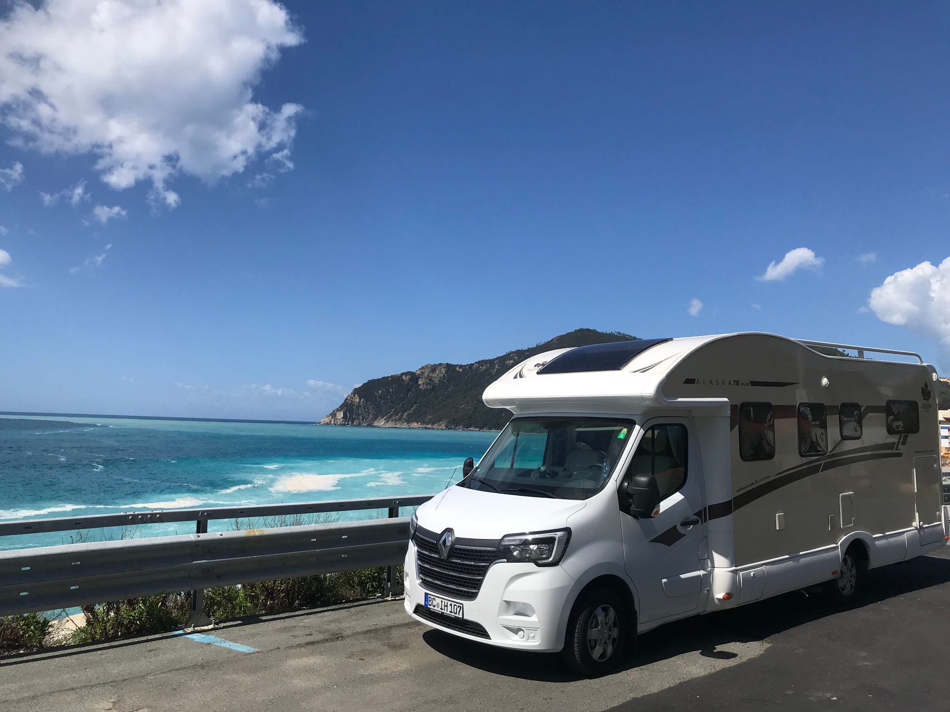 Ein weißes Wohnmobil ist am Straßenrand in der Nähe des Meeres geparkt.