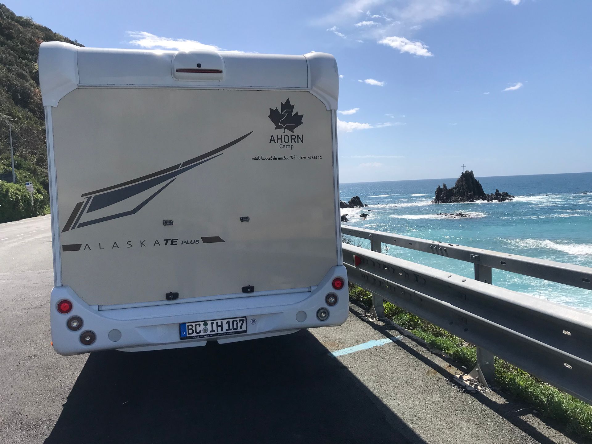 Ein weißes Wohnmobil ist am Straßenrand in der Nähe des Meeres geparkt.