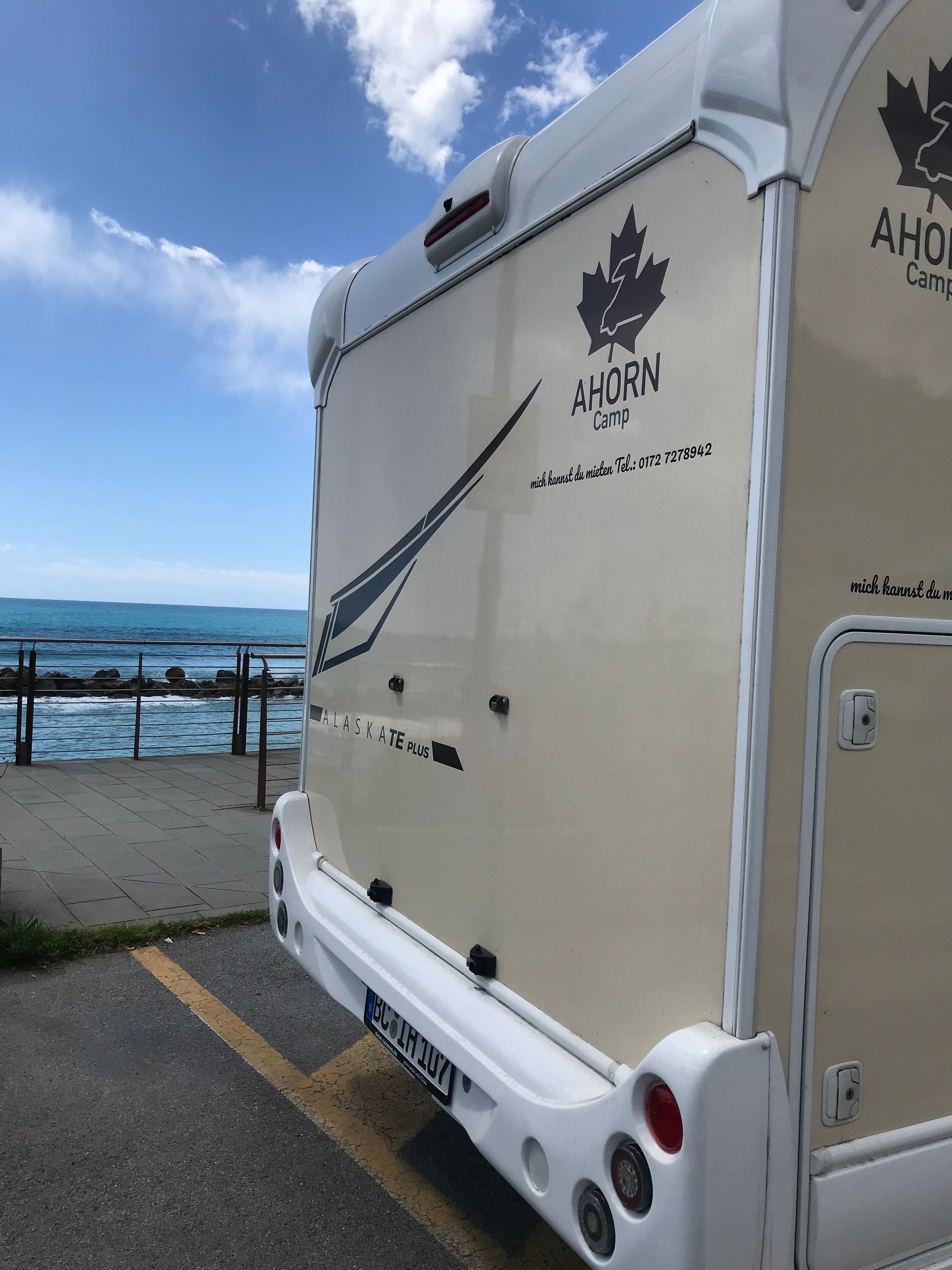 Ein weißes Wohnmobil steht auf einem Parkplatz in der Nähe des Ozeans