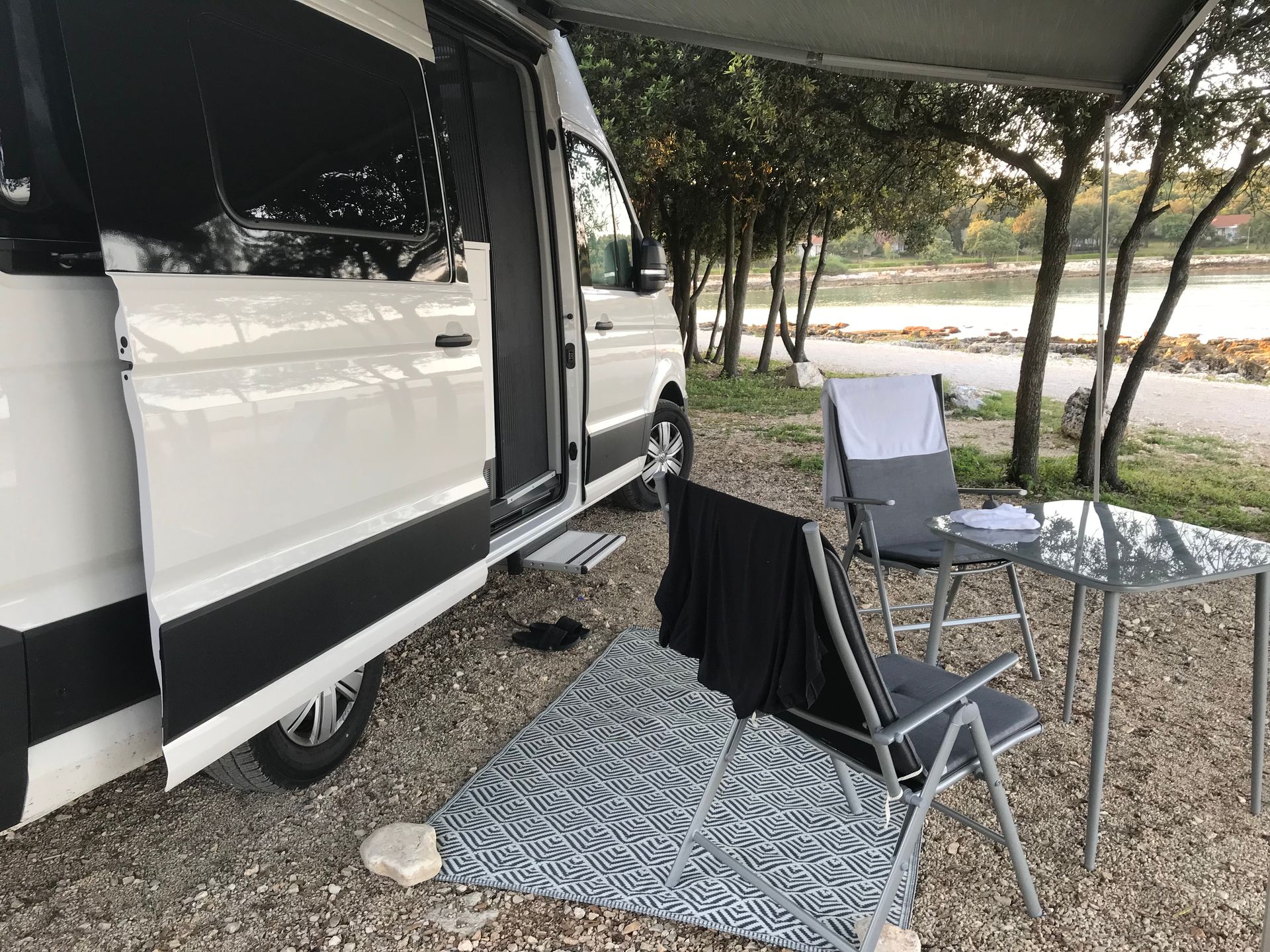 Ein weißer Lieferwagen steht auf einem Kiesplatz neben einem Tisch und Stühlen.