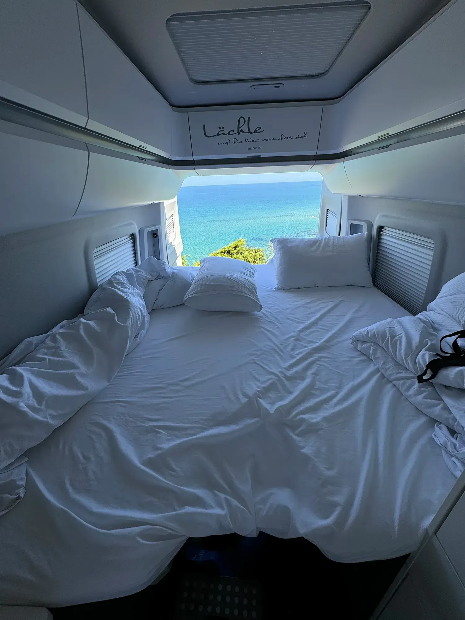 Ein Bett im hinteren Teil eines Lieferwagens mit Blick aufs Meer.