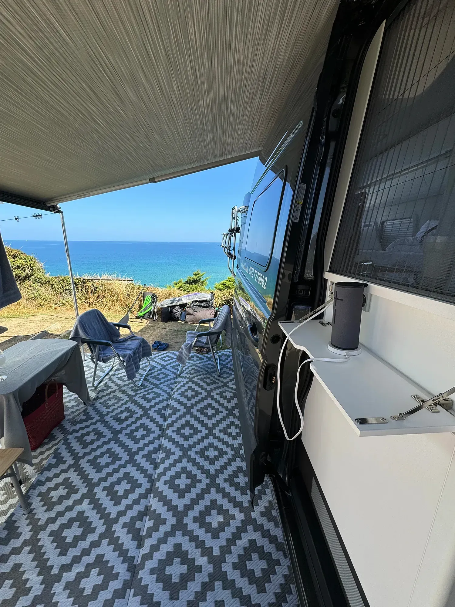 Ein Wohnmobil mit Blick aufs Meer und einem Tisch und Stühlen.