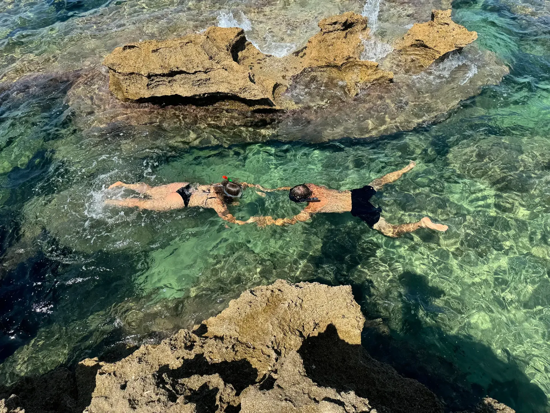 Zwei Leute schwimmen im Meer in der Nähe von Felsen.