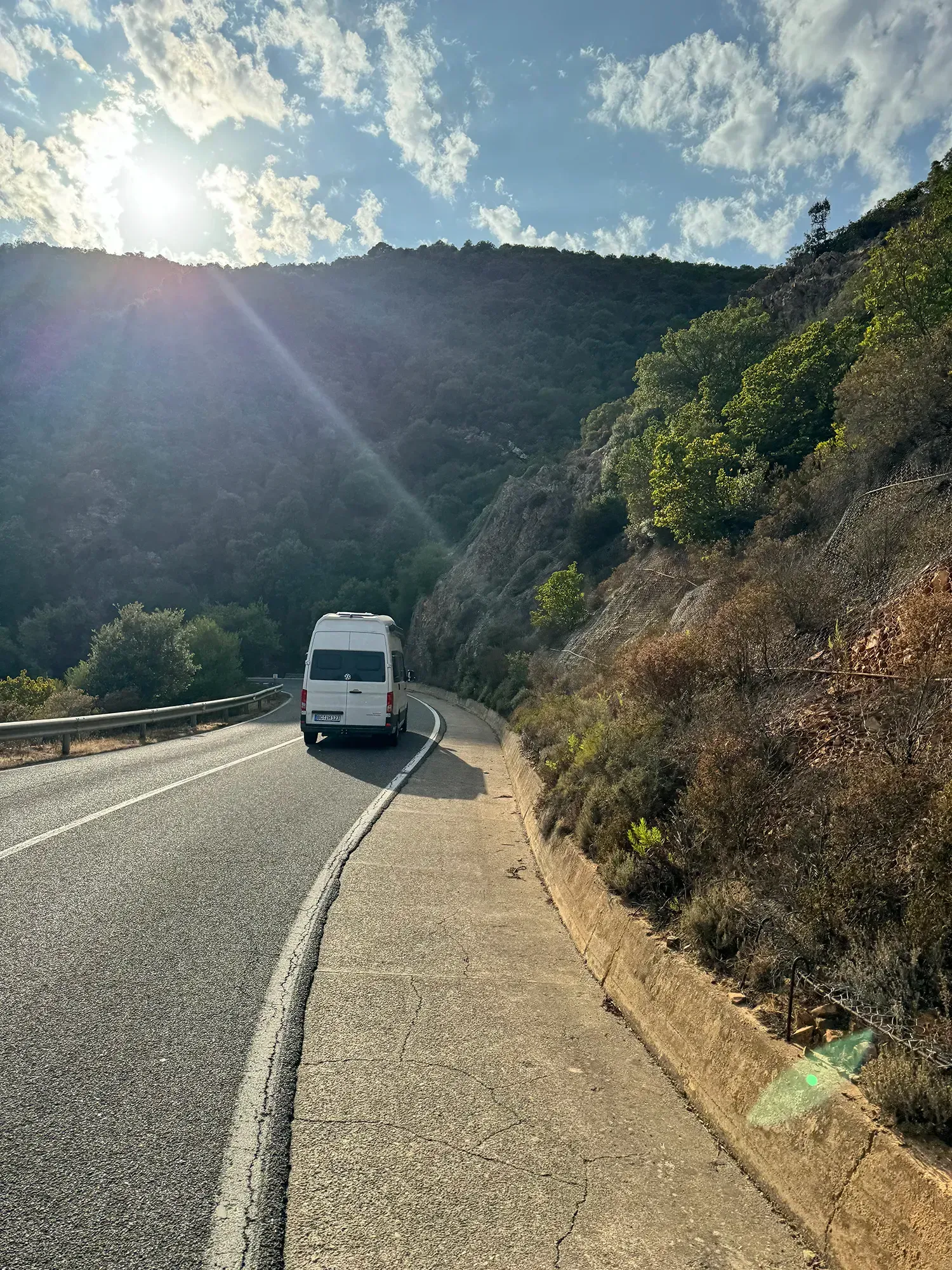 Ein weißer Lieferwagen fährt eine kurvige Straße entlang.