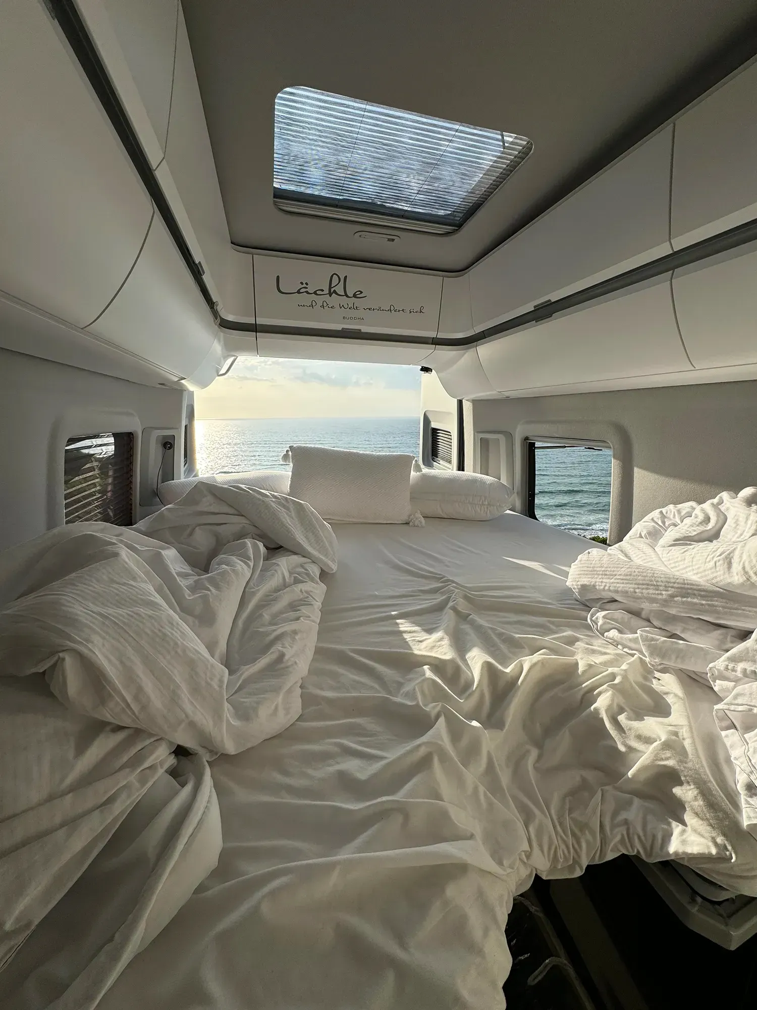 Im hinteren Teil eines Lieferwagens steht ein Bett mit Blick aufs Meer.