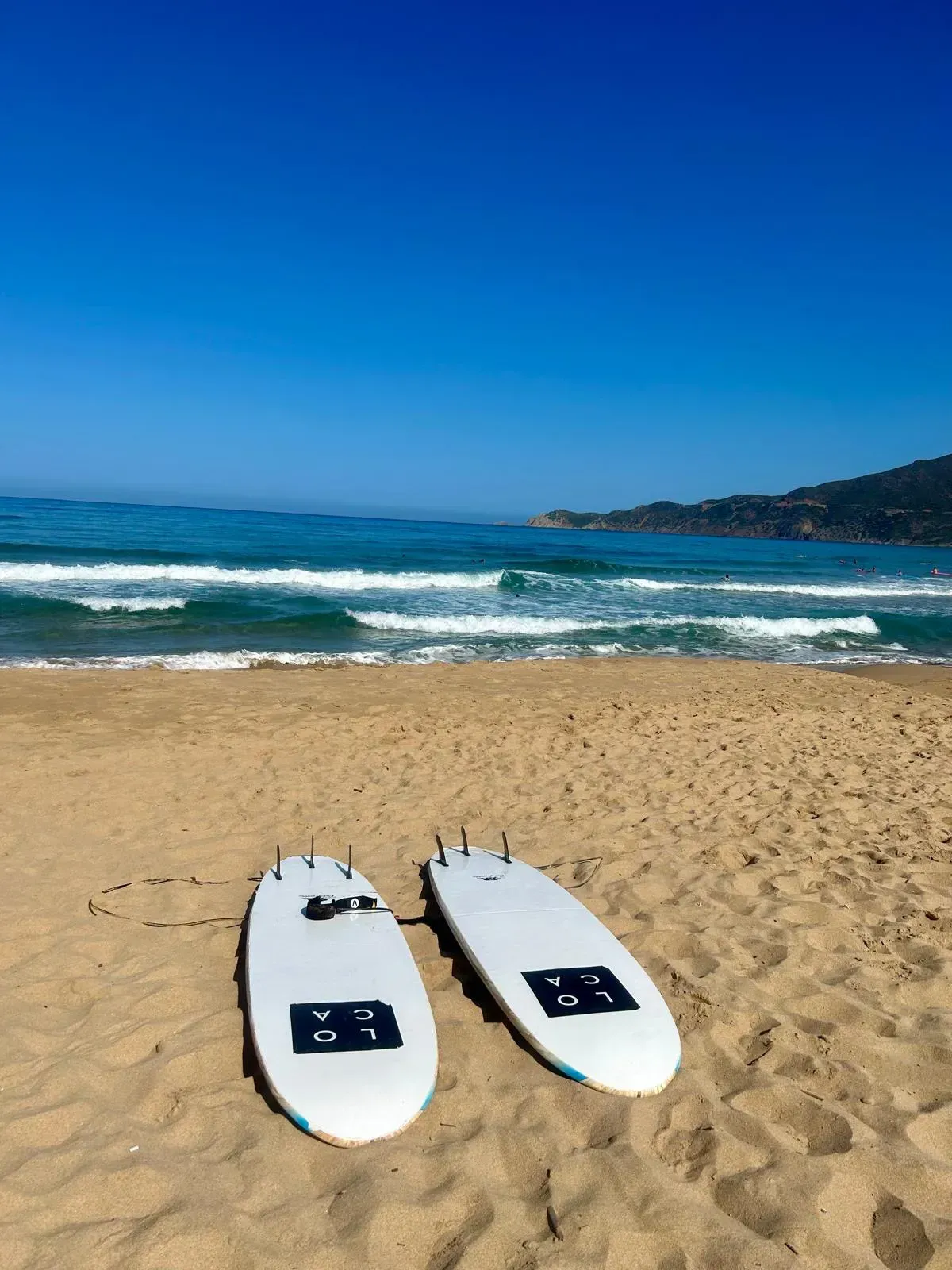 Zwei Surfbretter liegen an einem Sandstrand in der Nähe des Meeres.