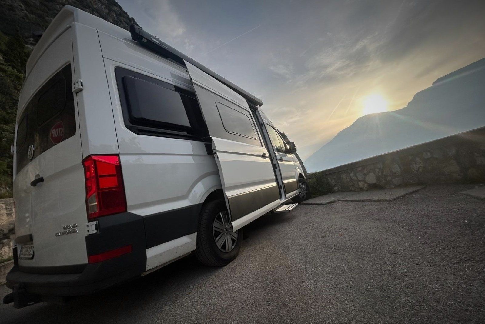 Ein weißer Lieferwagen steht mit offenen Türen am Straßenrand.