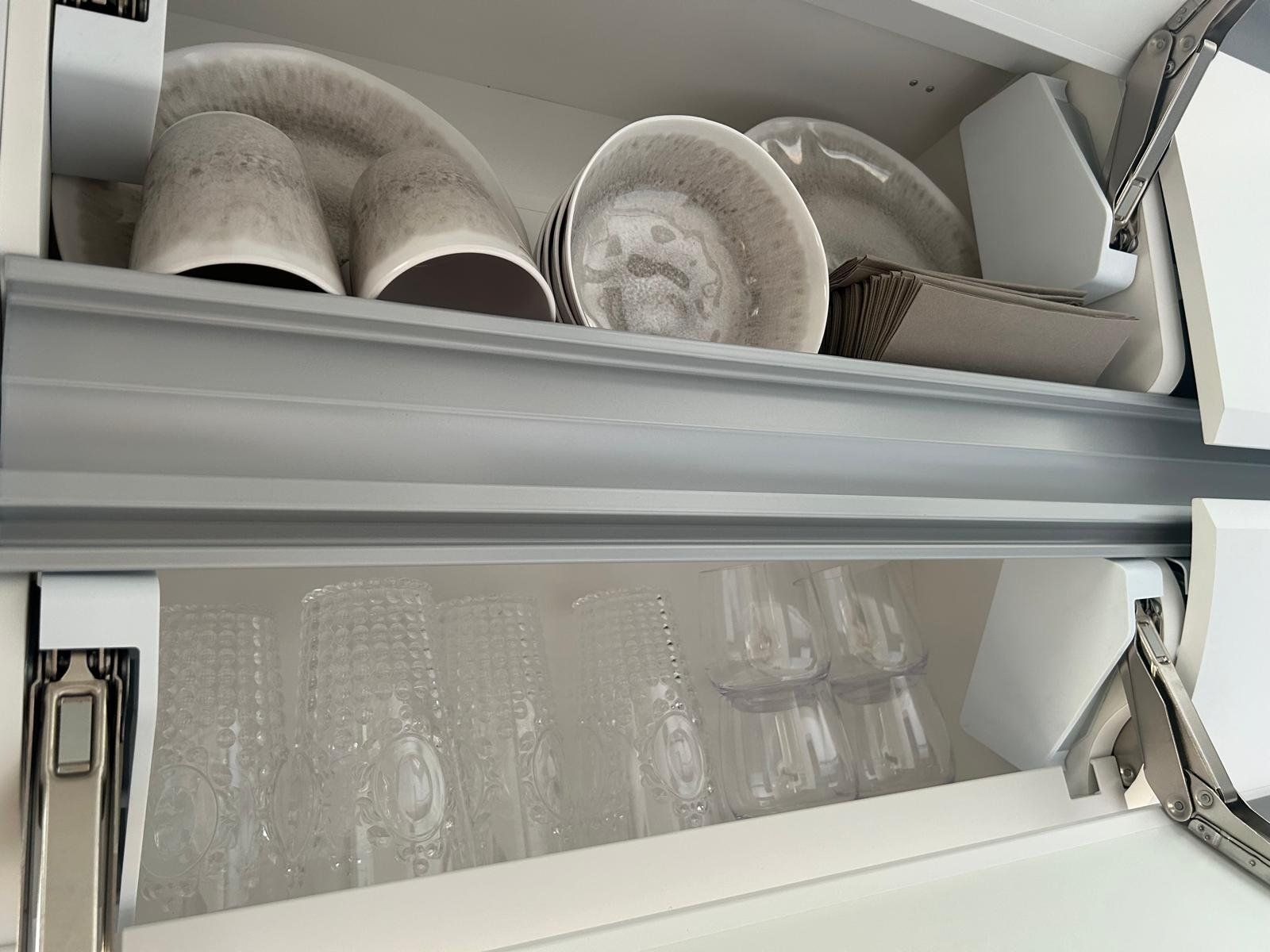 Ein Regal mit Tellern, Tassen und Gläsern darauf.