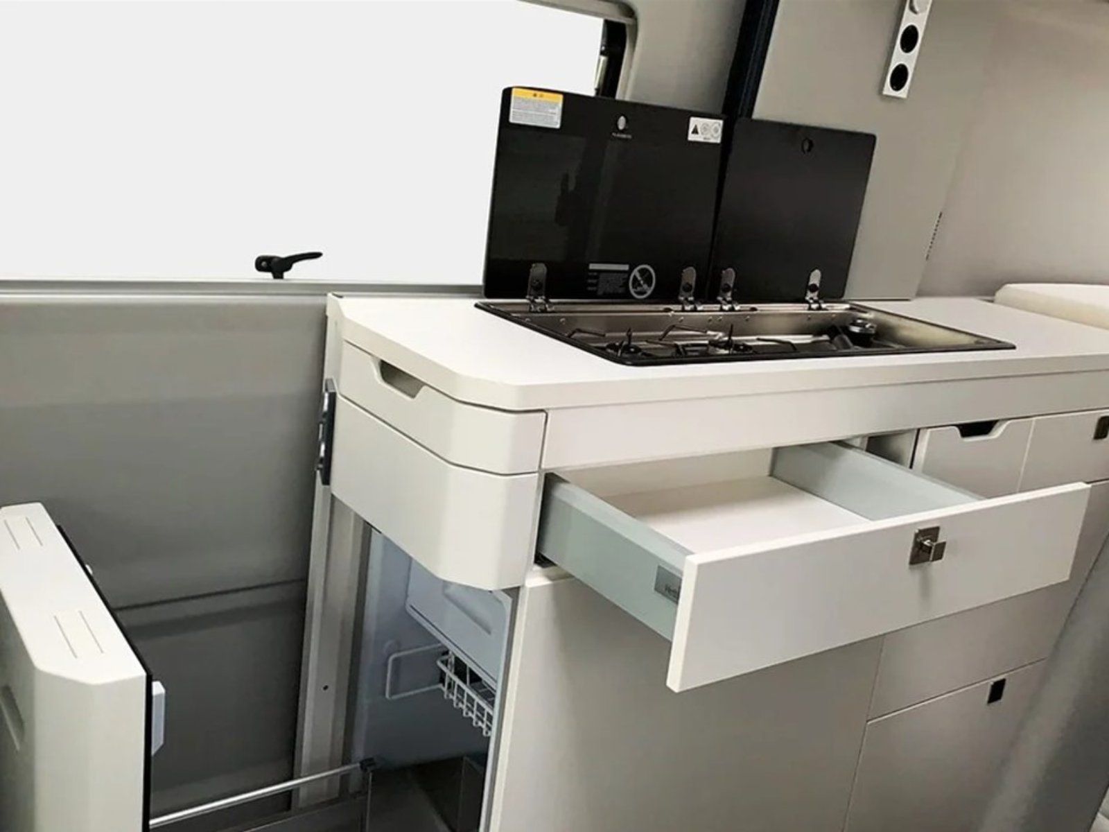 Eine Küche in einem Van mit einer offenen Schublade und einem Herd mit Backofen.