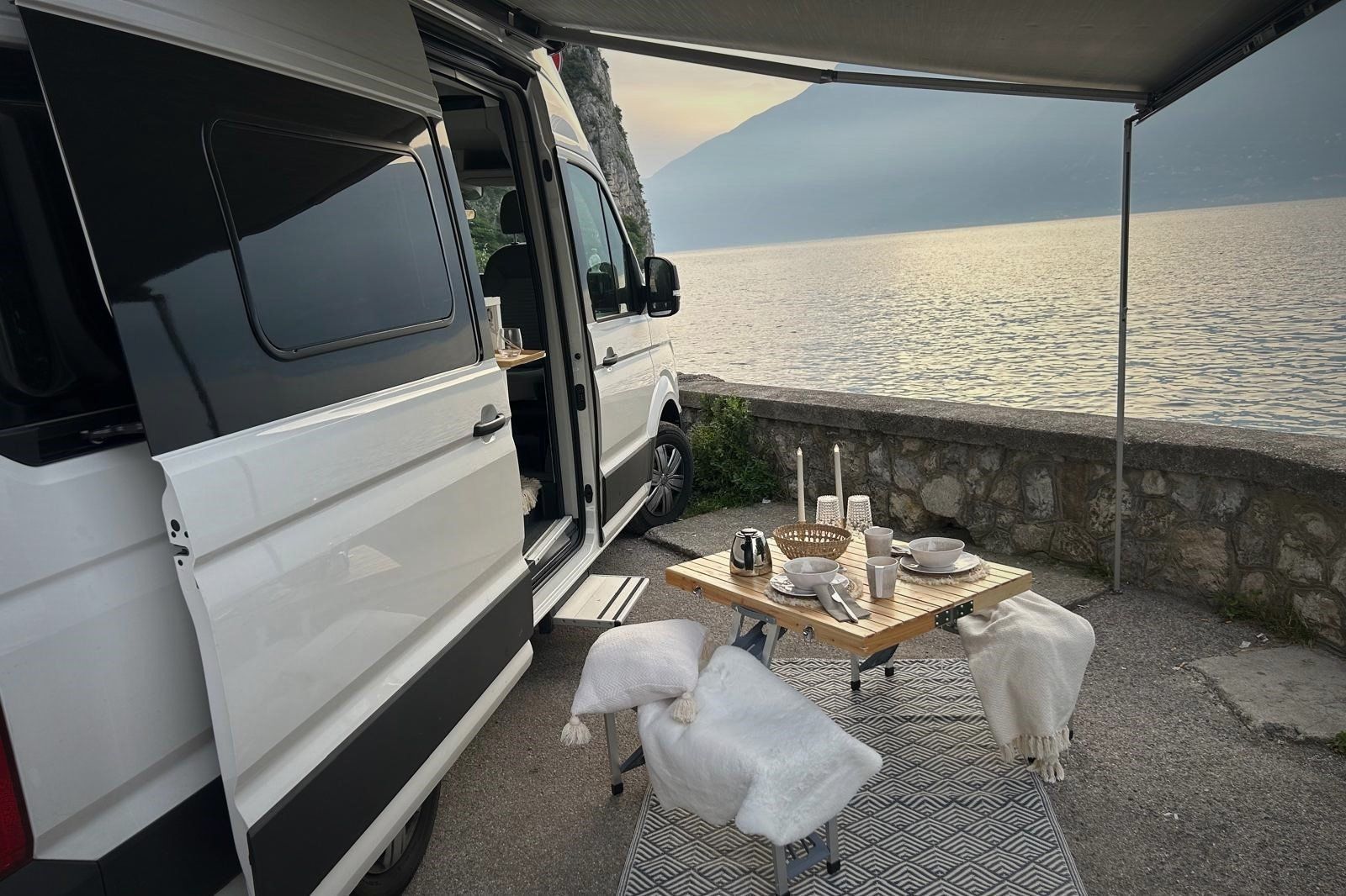 Ein weißer Lieferwagen parkt neben einem Tisch mit Kerzen darauf.