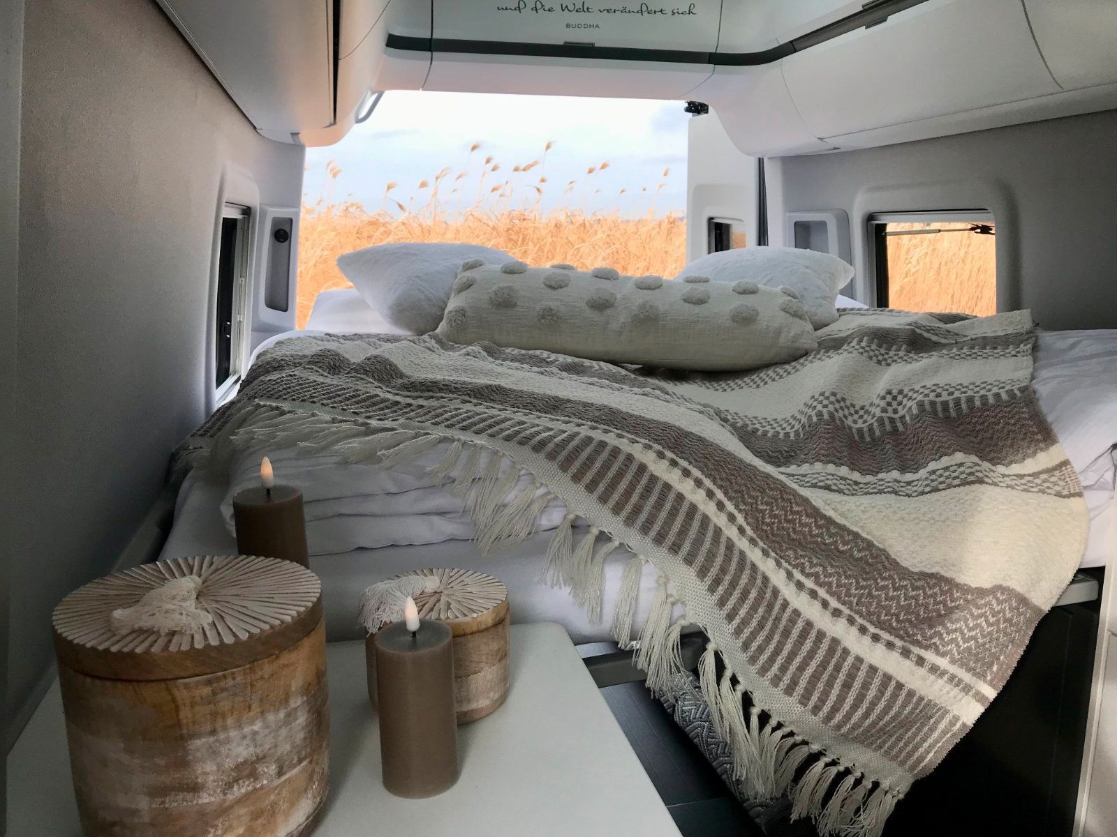 Ein Bett mit einer Decke und Kerzen auf der Ladefläche eines Lieferwagens