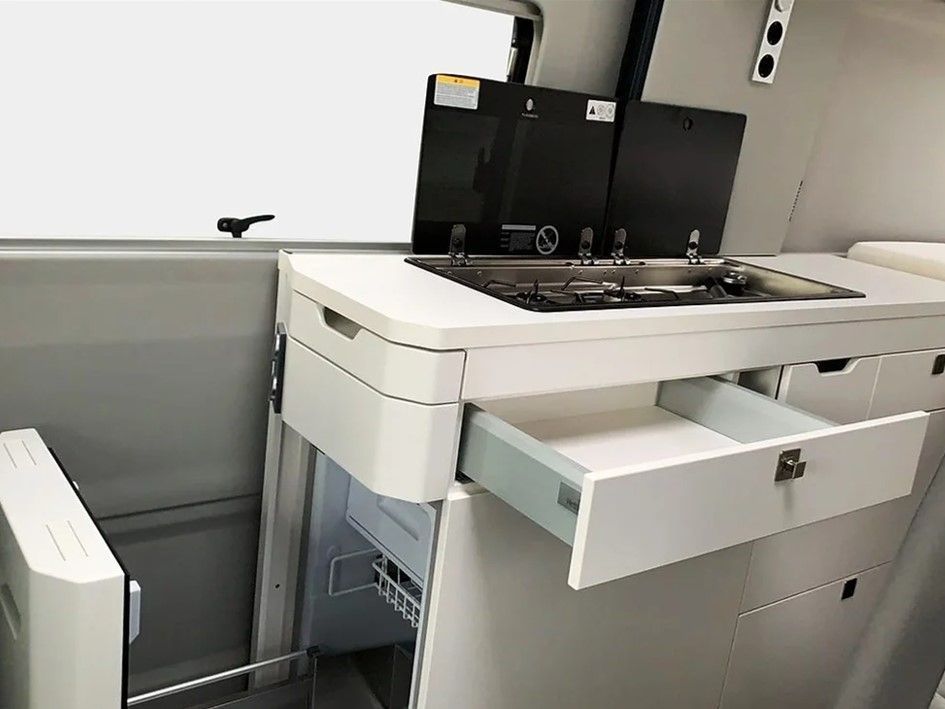 Eine Küche in einem Van mit Herd, Backofen und Schubladen.