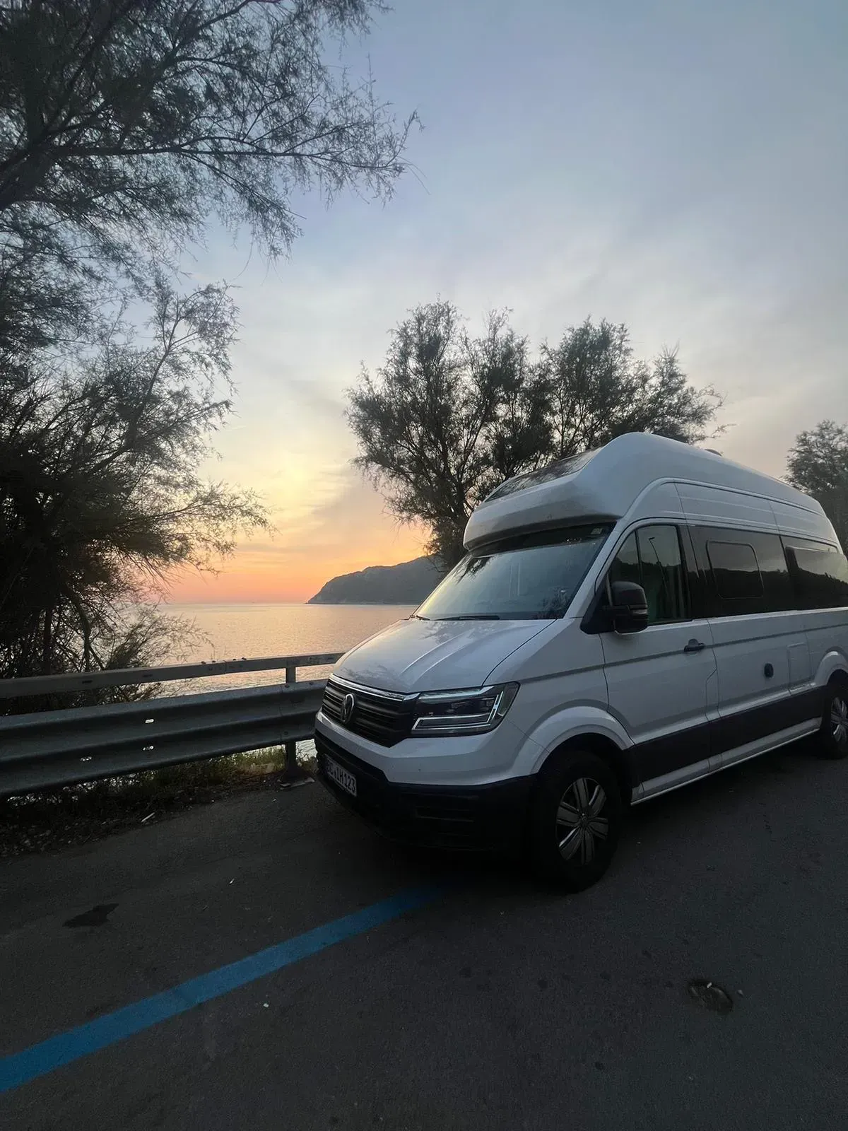 Ein weißer Lieferwagen ist am Straßenrand neben einem Gewässer geparkt.