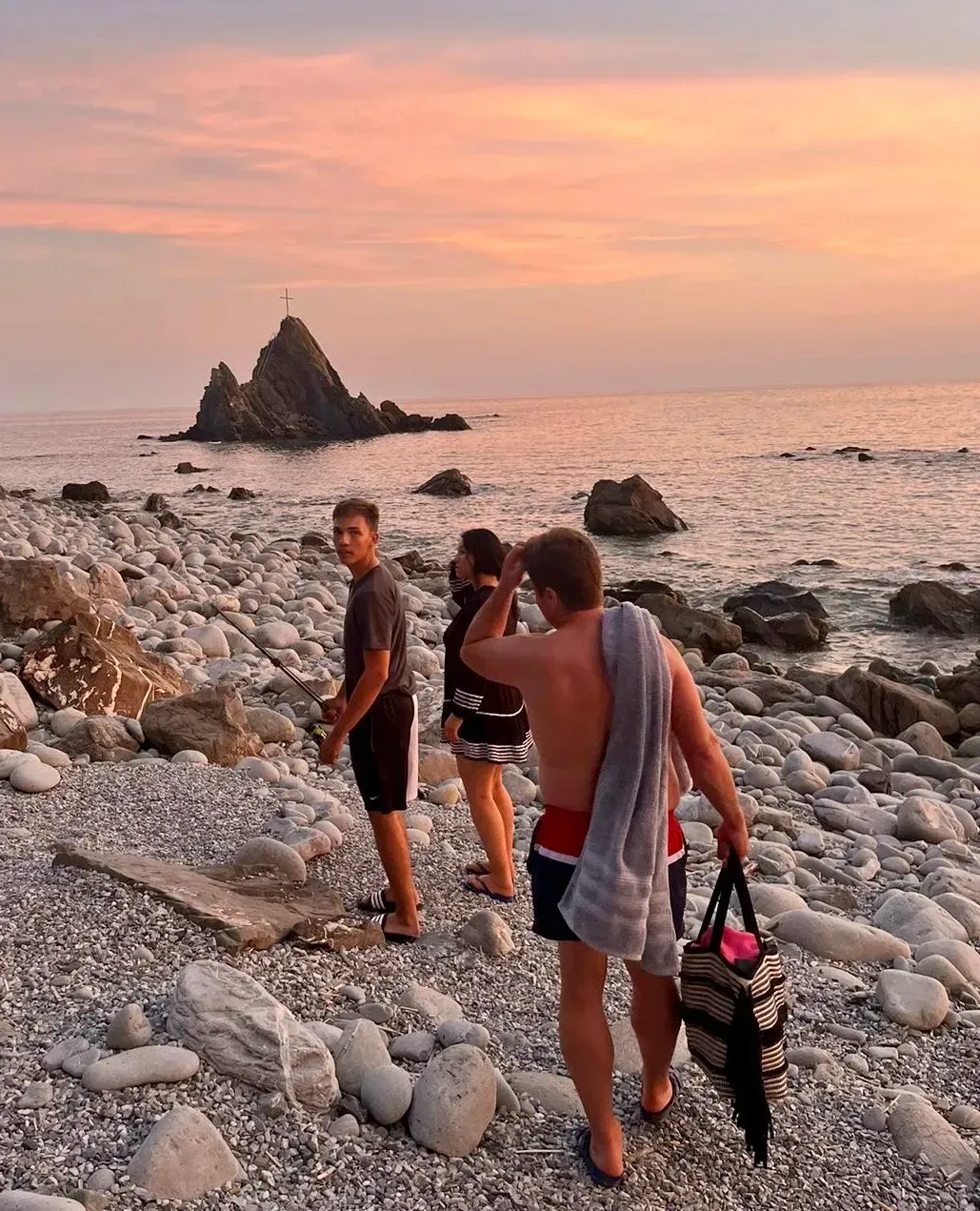 Eine Gruppe von Leuten steht an einem felsigen Strand in der Nähe des Meeres.