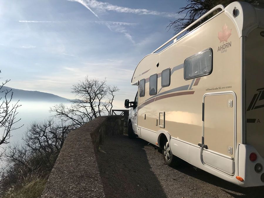 Ein Wohnmobil ist am Straßenrand mit Aussicht auf einen See geparkt.