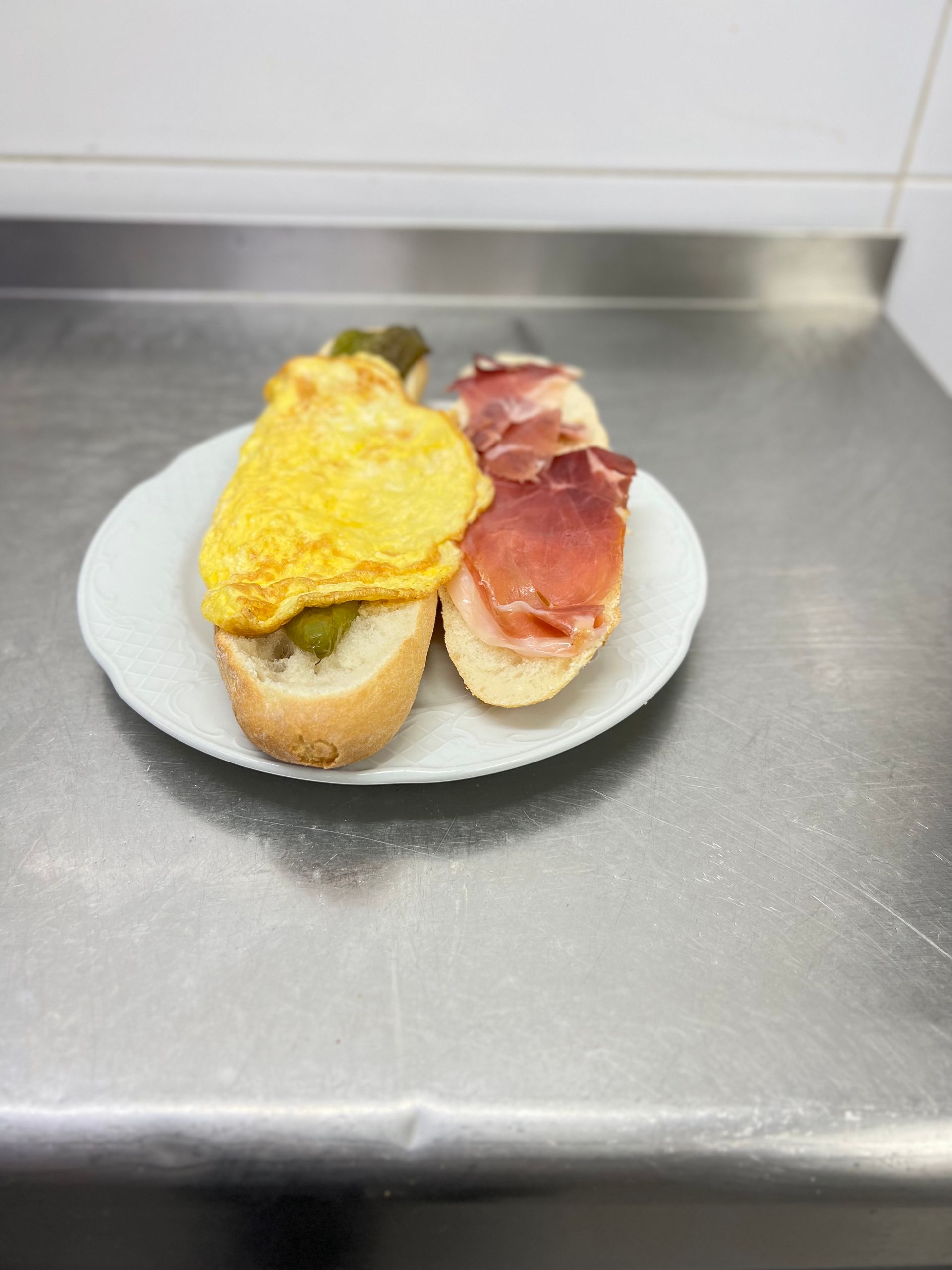 Plato de tapas: tortilla y jamón sobre rebanadas de pan.