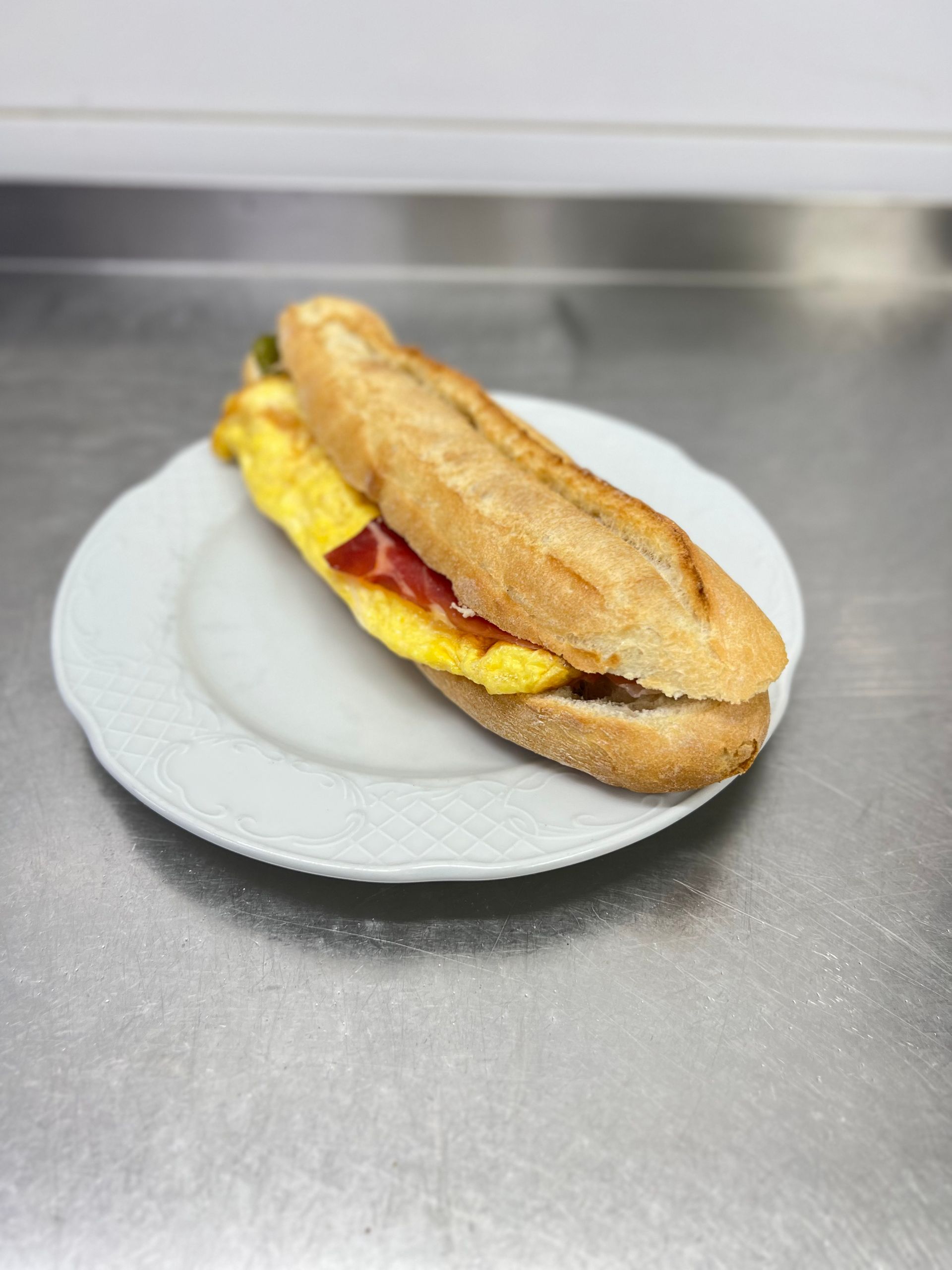 Sándwich en baguette, relleno de tortilla amarilla y carne
