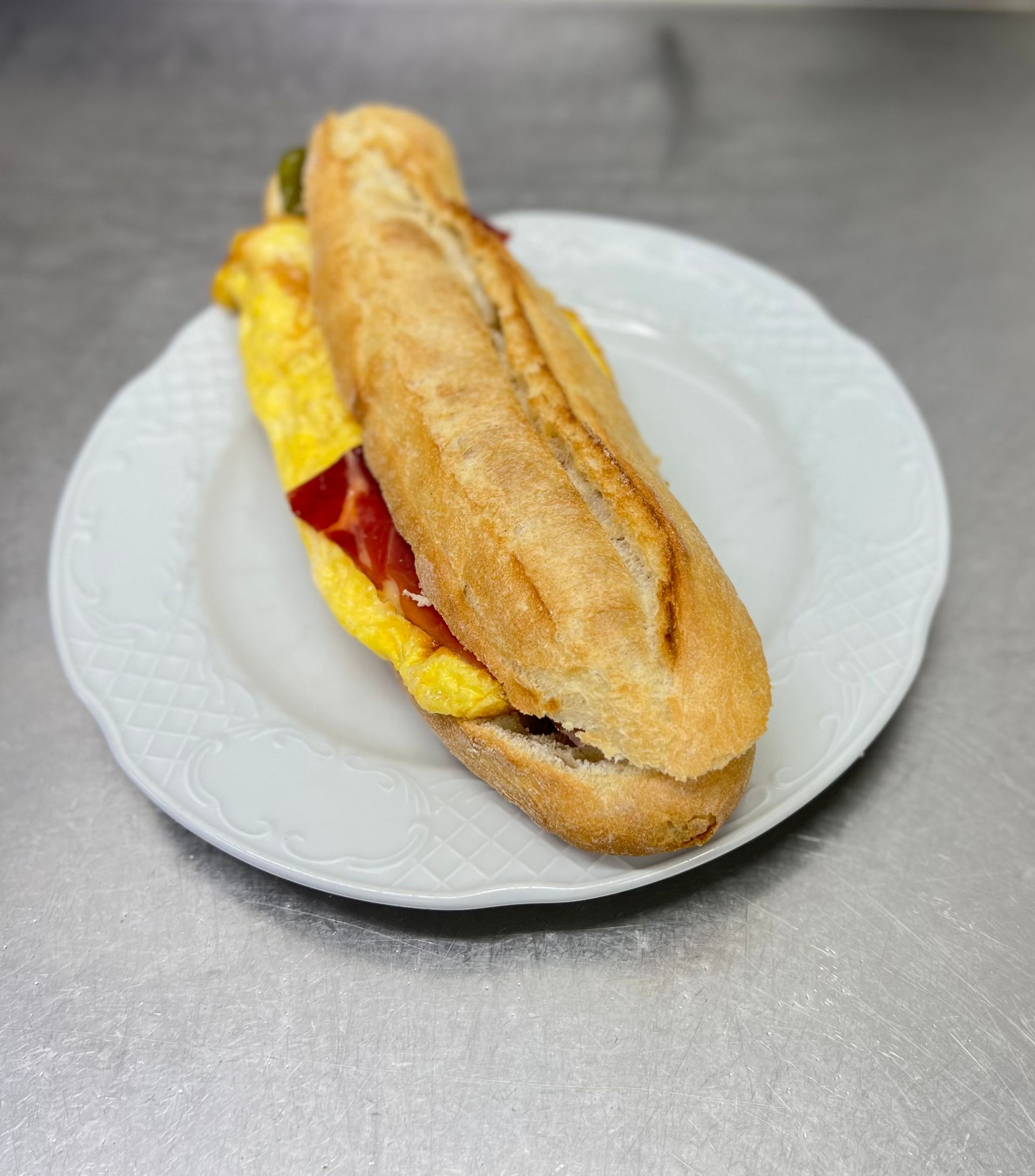 Sándwich de huevo y tocino en un plato blanco.
