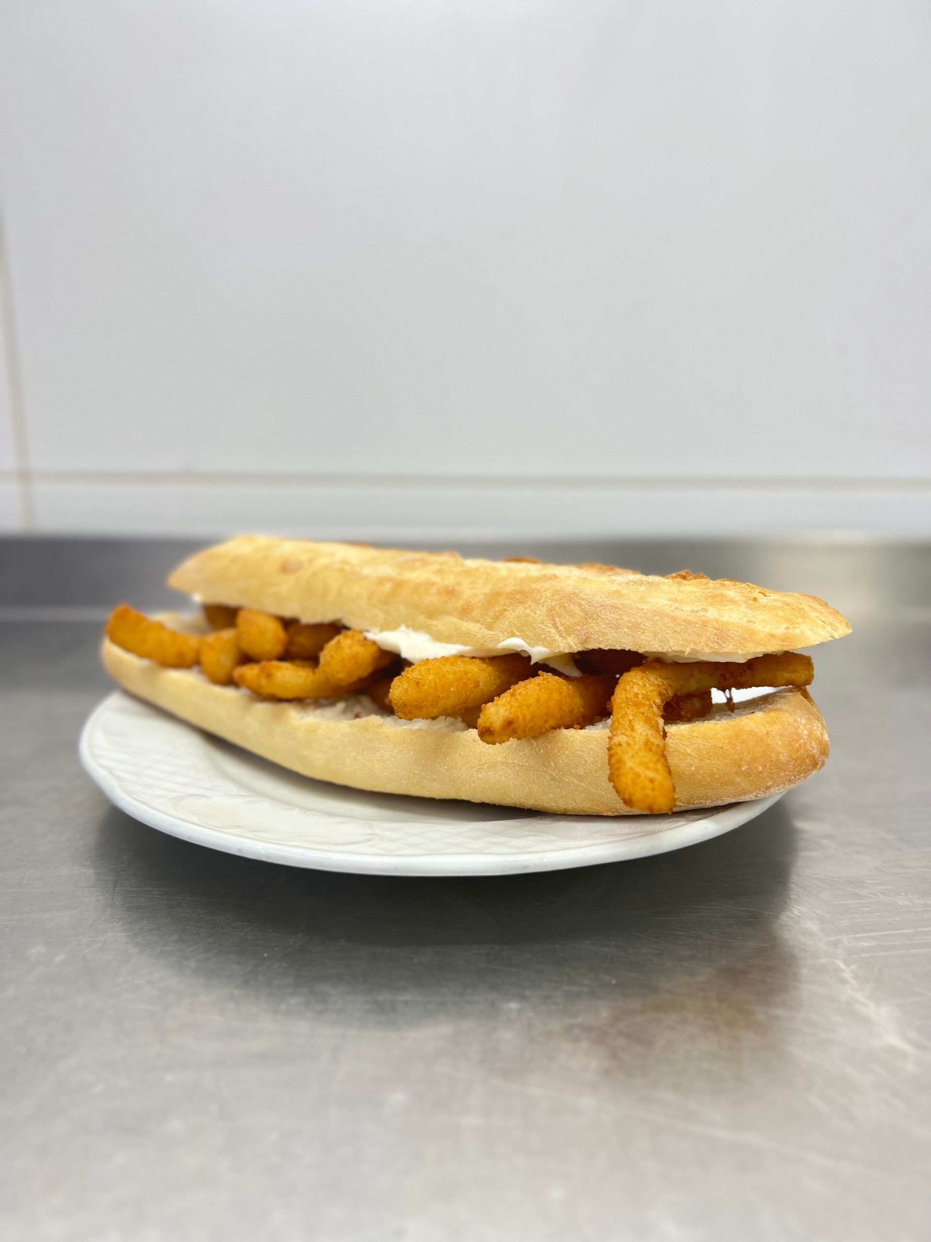 Sándwich con comida frita y salsa en un plato.